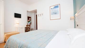 Una camera da letto con un letto, una scrivania, una sedia, una TV e un quadro appeso alla parete.