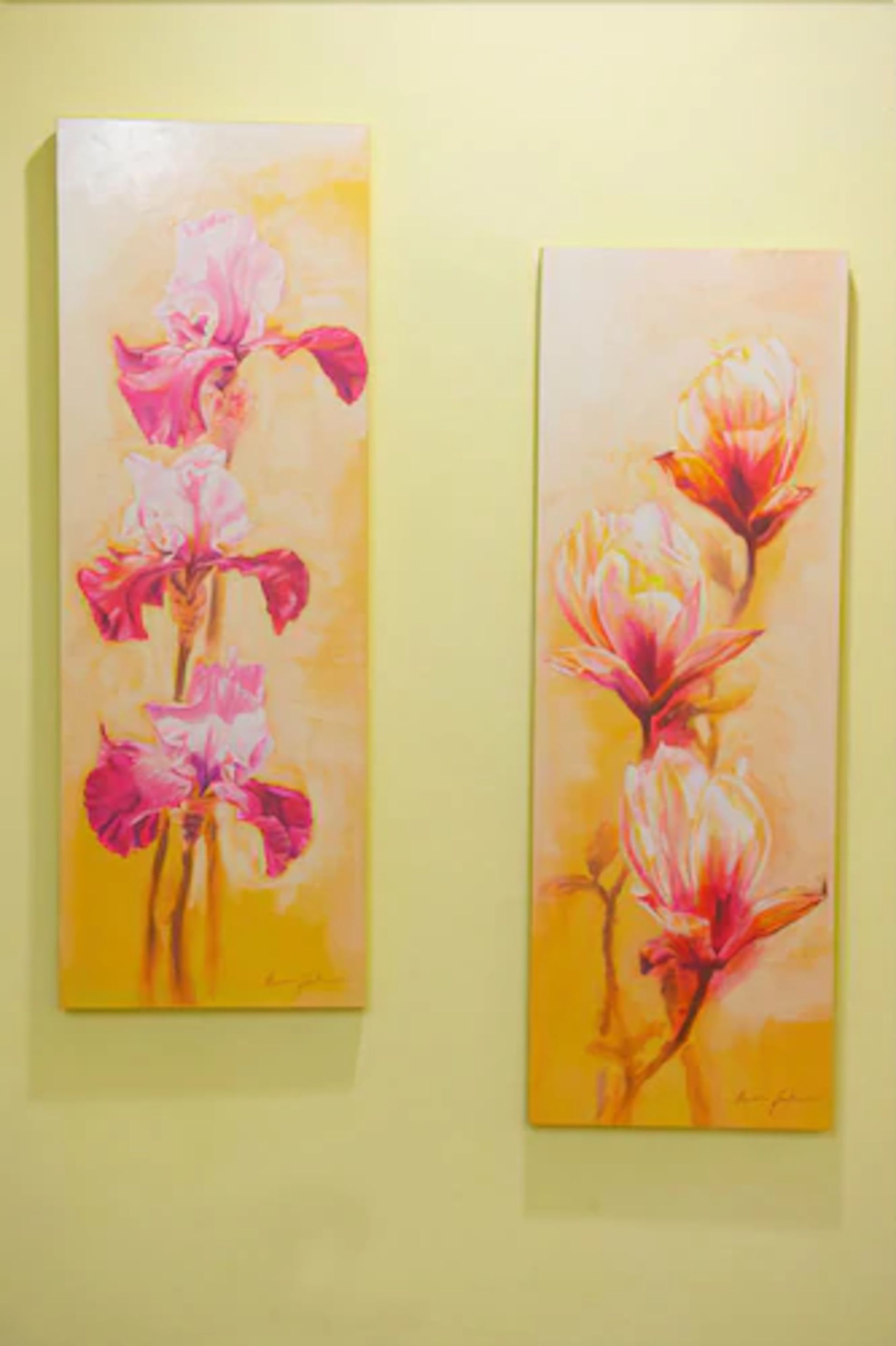 Two paintings of flowers on a wall.