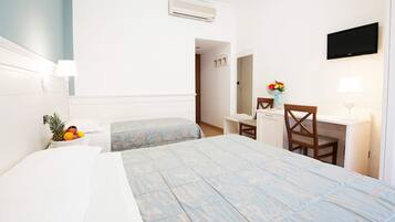 A hotel room with a bed, a desk, a chair, a TV, and a mirror.