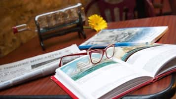 A book, glasses, and a newspaper on a wooden table.