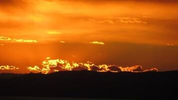 Ein Sonnenuntergang mit Wolken über einem Gebirge.