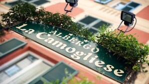 Een hangend bord met de naam 'La Camogliese' en een sterretje, wat duidt op een hotel of etablissement.