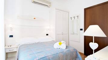 Quarto de hotel com cama, mesa de cabeceira, guarda-roupa e ar condicionado.