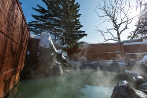 A hot spring area with a wooden fence, rocks, and snow-covered trees. - The Green Leaf Niseko Village, Tapestry Collection by Hilton (Niseko)