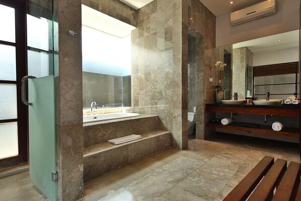 A modern bathroom with a glass shower enclosure, a marble sink vanity, and a bench.