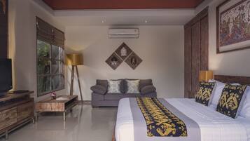 A modern hotel room with a large bed, a sofa, a TV, and a desk.