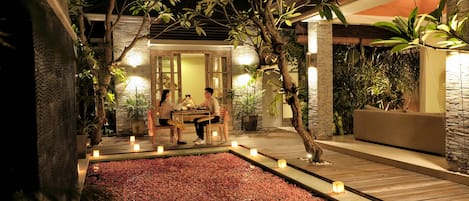 An outdoor seating area with a stone wall, wooden deck, and potted plants.