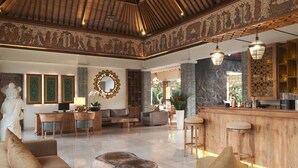 A spacious lobby with a wooden ceiling, a stone wall, and a bar area. - The Wolas Villa & Spa (Seminyak)