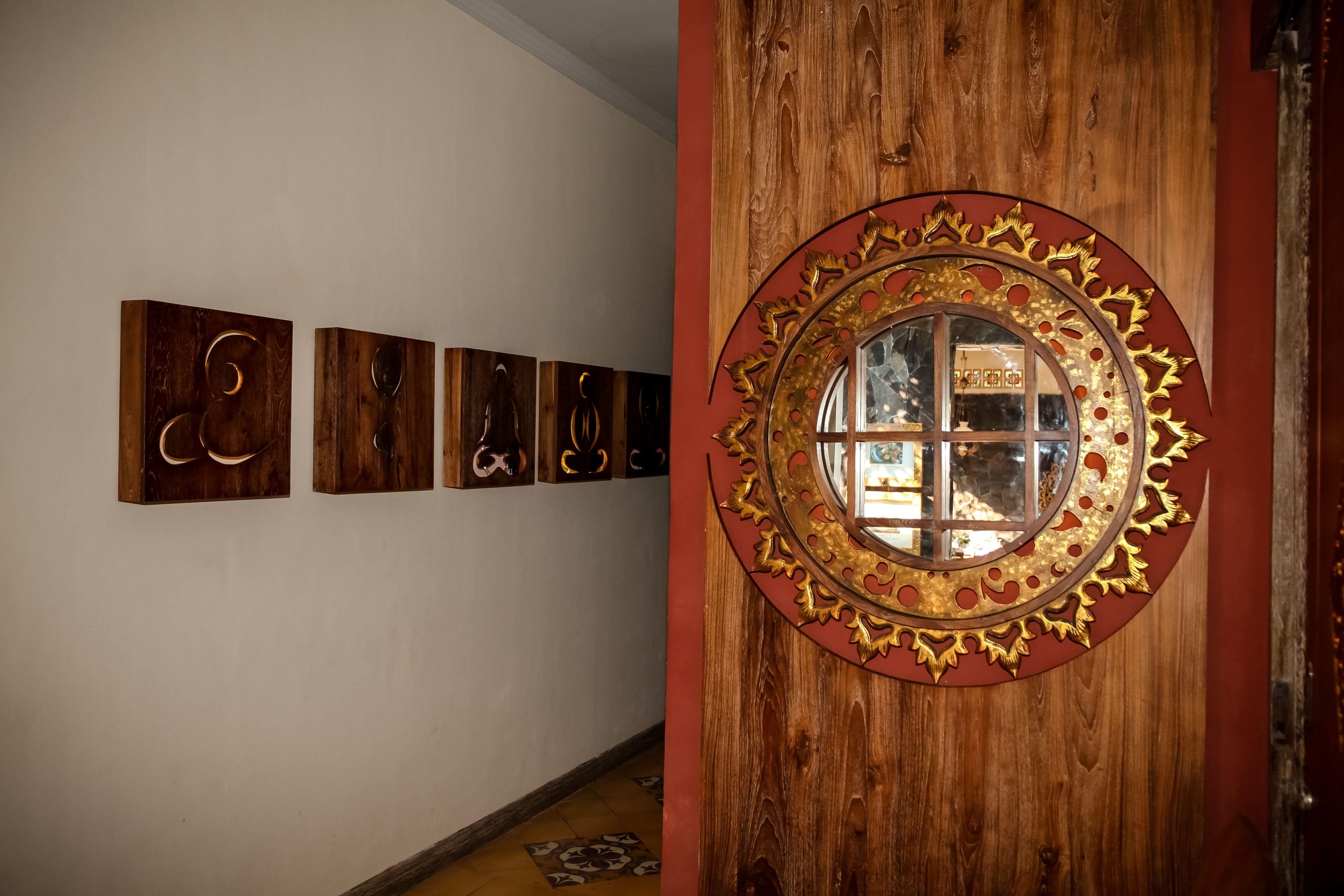 A hallway with wooden wall art and a decorative mirror with a gold frame.