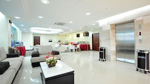 A modern hotel lobby with a reception desk, seating area, and an elevator. - Hallmark View Hotel (Malacca City)