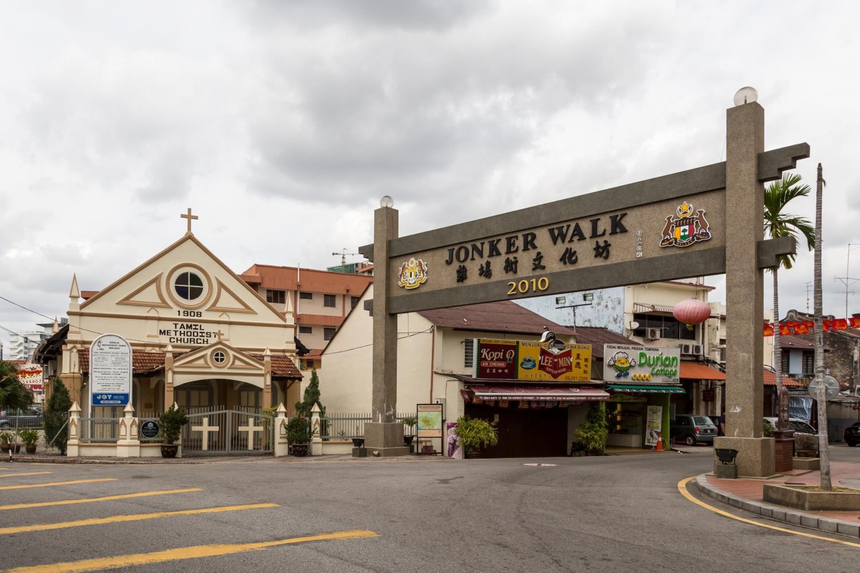 Uma igreja com uma cruz no topo, uma placa com a inscrição 'JONKER WALK 2010' e um restaurante Durian Cottage.