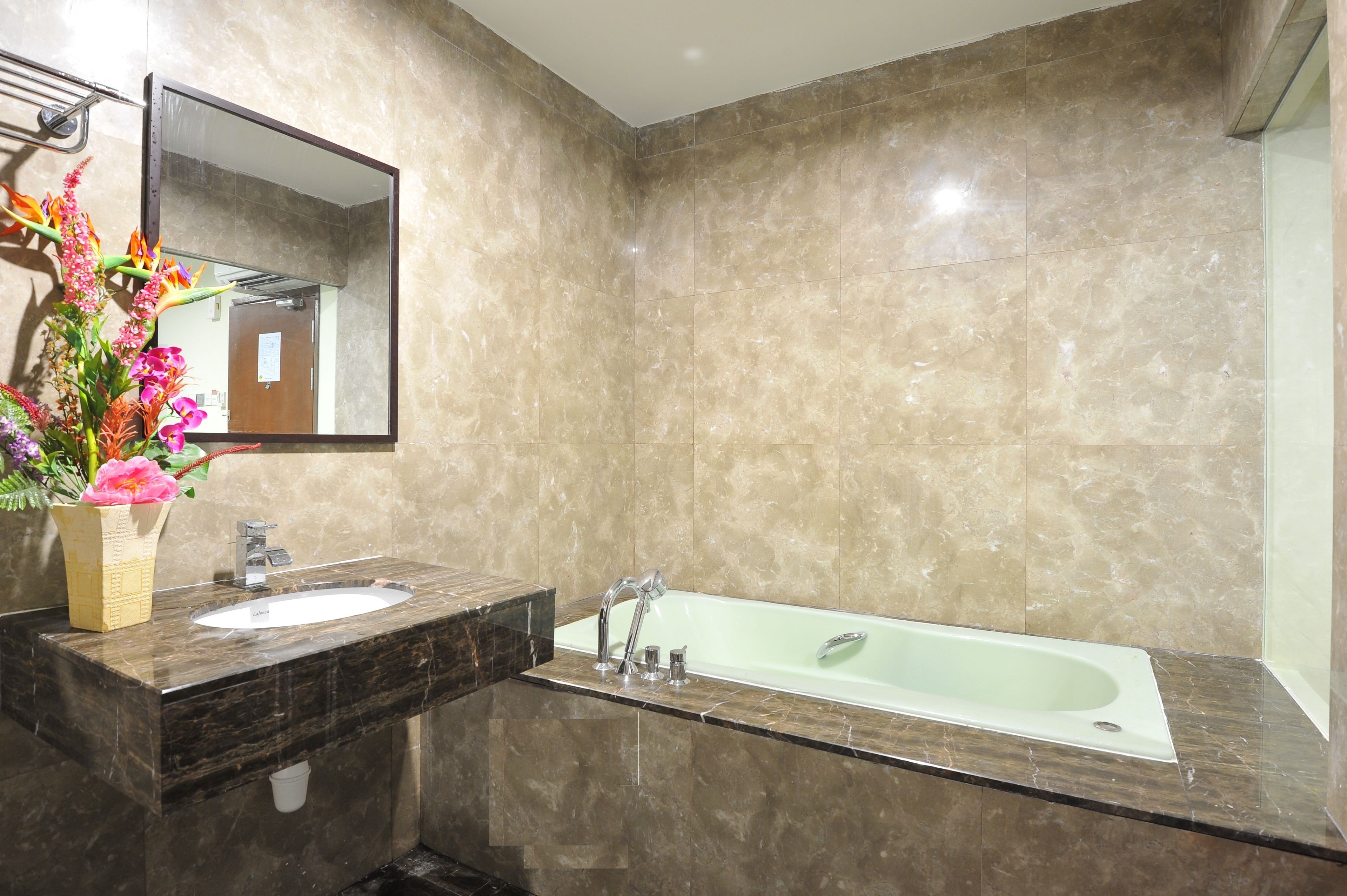 Un baño con lavamanos de mármol, bañera y espejo.