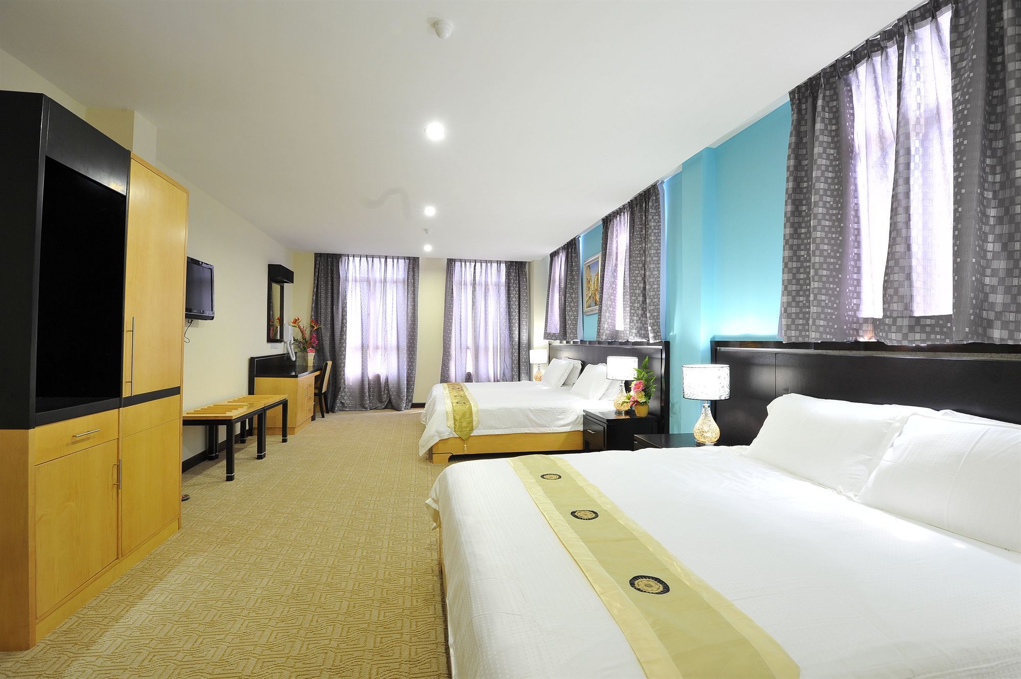 A hotel room with two beds, a desk, a TV, and a bathroom.