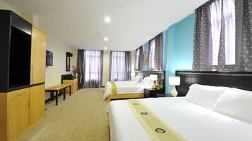 A hotel room with two beds, a desk, a TV, and a bathroom.