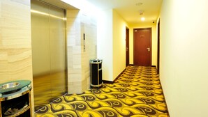 A hotel hallway with a patterned carpet, an elevator, a trash can, and a door at the end. - Hallmark View Hotel (Malacca City)