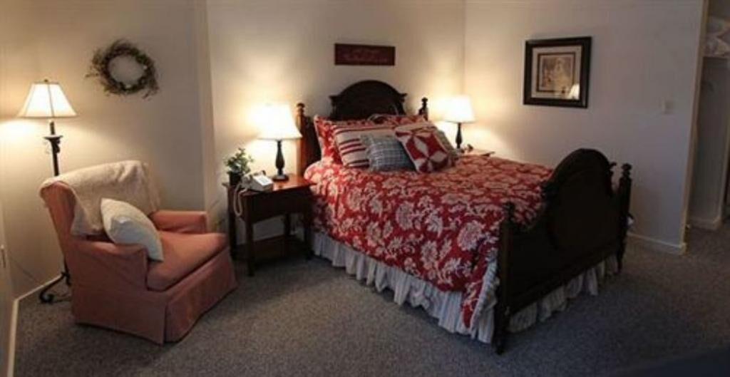 A bedroom with a bed, two bedside tables, a chair, and a lamp.