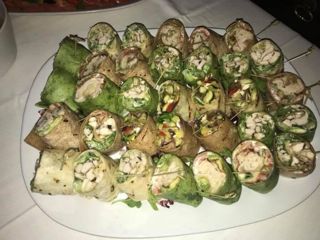 Un plato de wraps con diferentes rellenos, entre ellos verduras y carnes, dispuesto sobre un plato blanco.