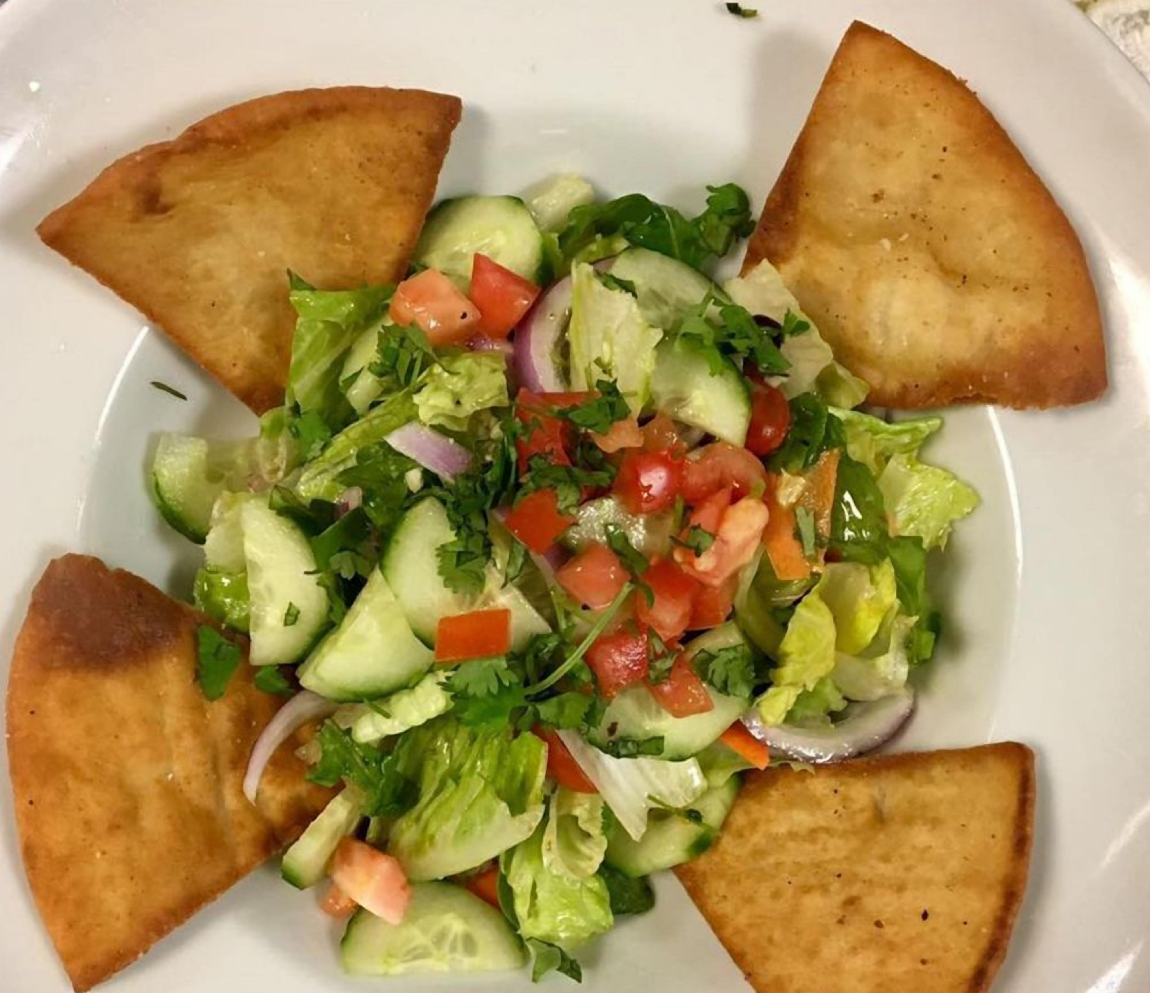 A plate with a salad and four pieces of toasted bread.