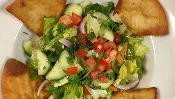 A plate with a salad and four pieces of toasted bread.
