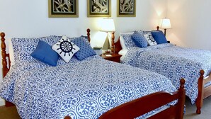 A double bed with a blue and white patterned bedspread, two bedside tables with lamps, and three framed pictures on the wall. - Camelot Restaurant & Inn (Clarks Summit)