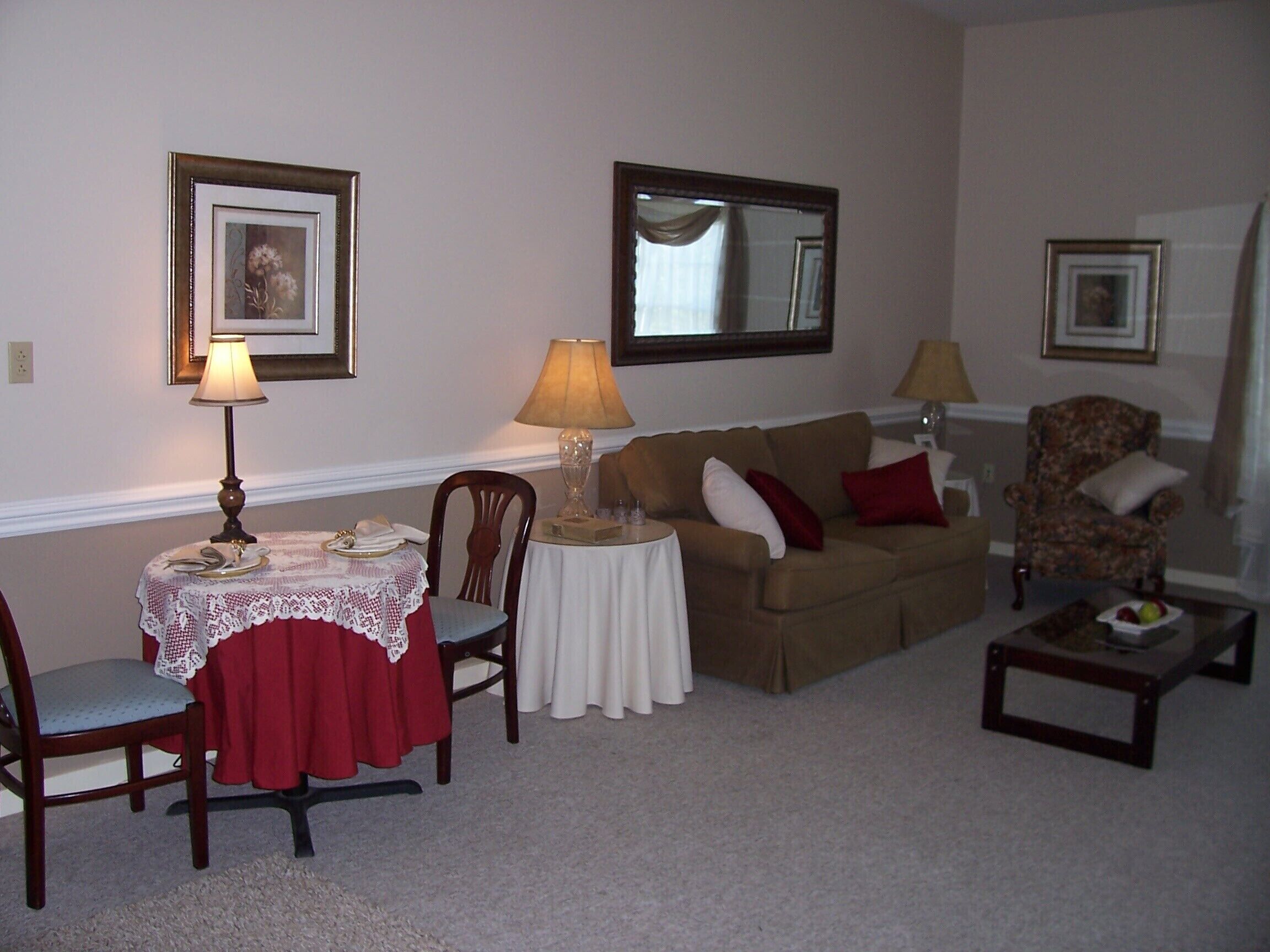 A living room with a dining table, two chairs, a sofa, a coffee table, and two lamps.