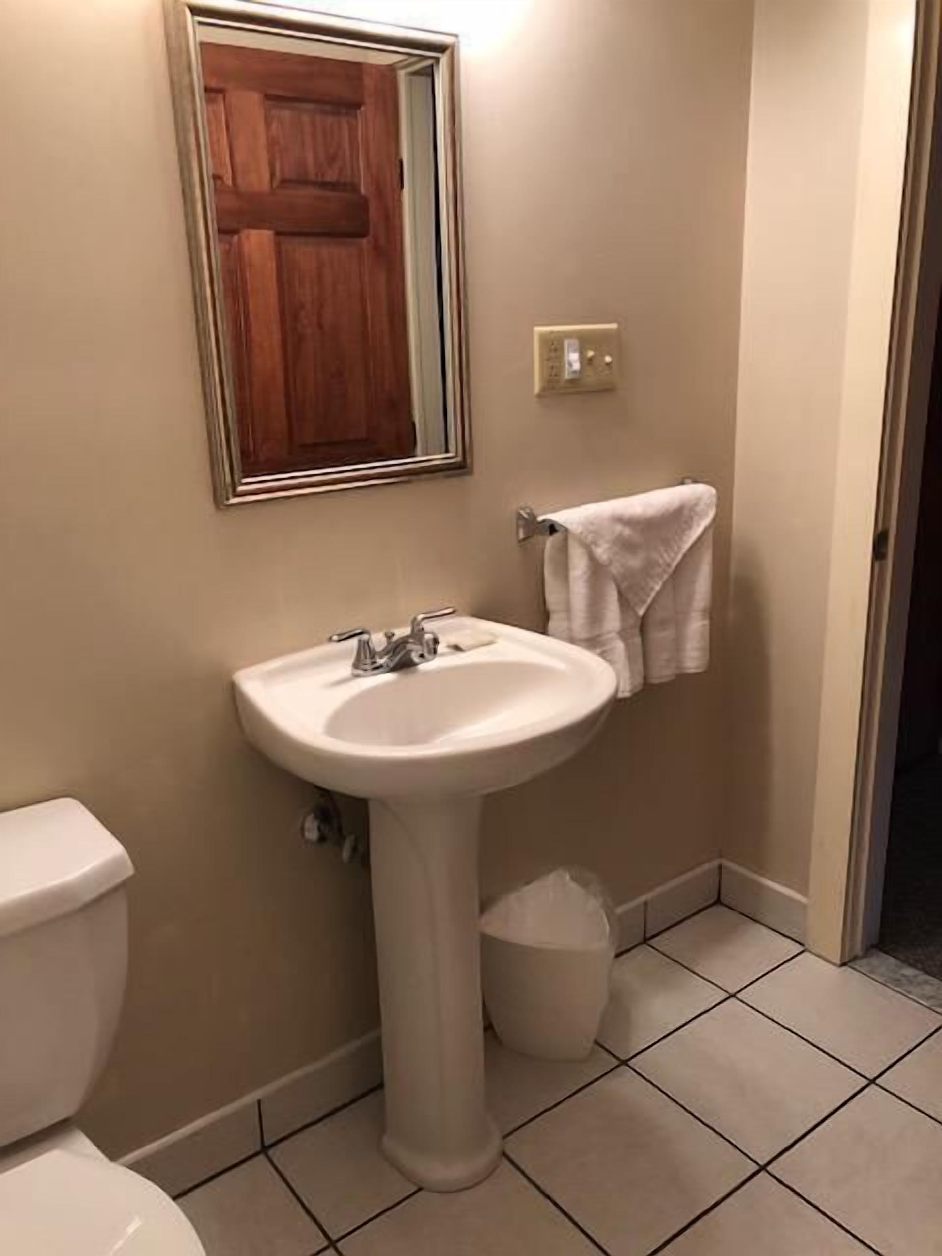 Un bagno con lavandino bianco, uno specchio, un porta asciugamani e un water.