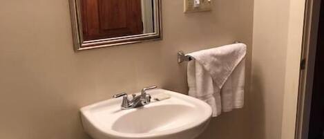 Un bagno con lavandino bianco, uno specchio, un porta asciugamani e un water.