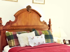 A wooden bed with a curved headboard, multiple pillows, and a red blanket.