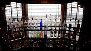 A bar area with shelves of various liquor bottles, a window with a view of the outside, and a grid-like window structure. - Camelot Restaurant & Inn (Clarks Summit)