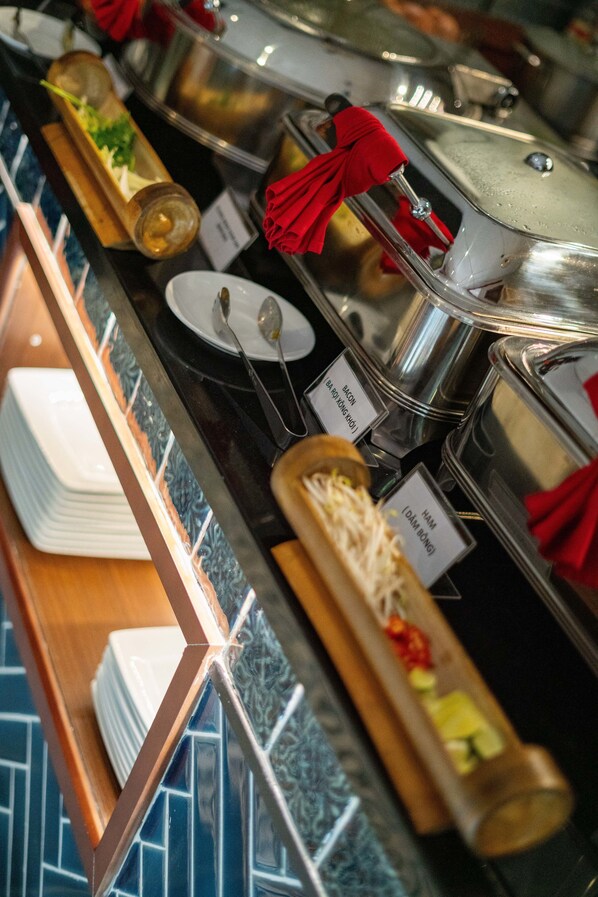 A buffet setup with labeled containers for various food items like ham, bacon, and cheese.