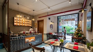 Un restaurante con barra de azulejos, mesas de comedor con servilletas rojas y un árbol de Navidad.