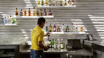 A bar area with shelves of liquor bottles, a man in a yellow shirt, and a phone on the counter.