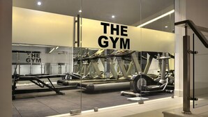 Un gimnasio moderno con paredes de vidrio, diversos equipos de ejercicio y un letrero que dice "THE GYM".