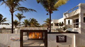Un edificio moderno con un cartel que dice "THE PARK Calangute Goa" y un camino que lleva a una estructura de madera.