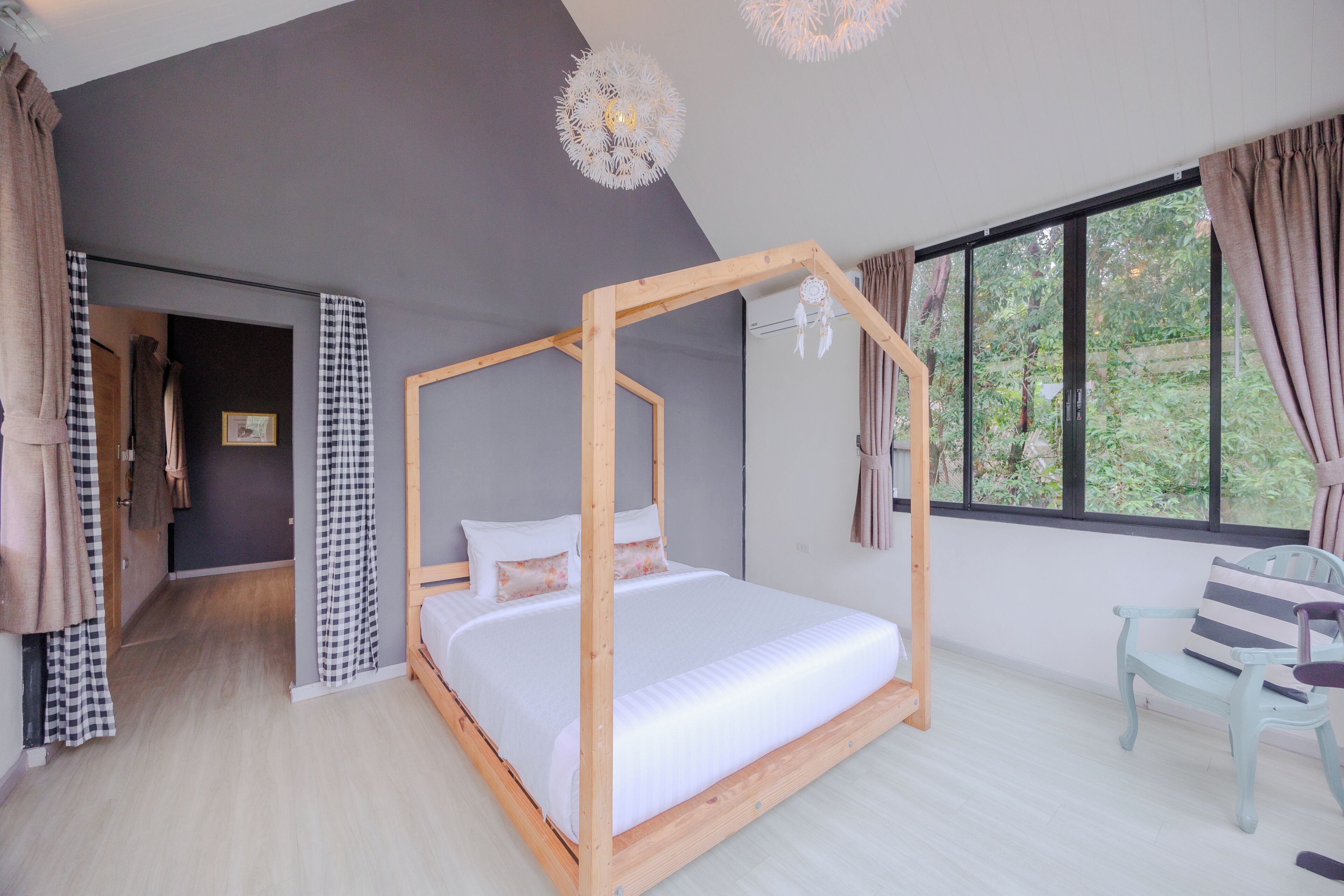 A bedroom with a four-poster bed, a window with curtains, a chair, and a door leading to another room.