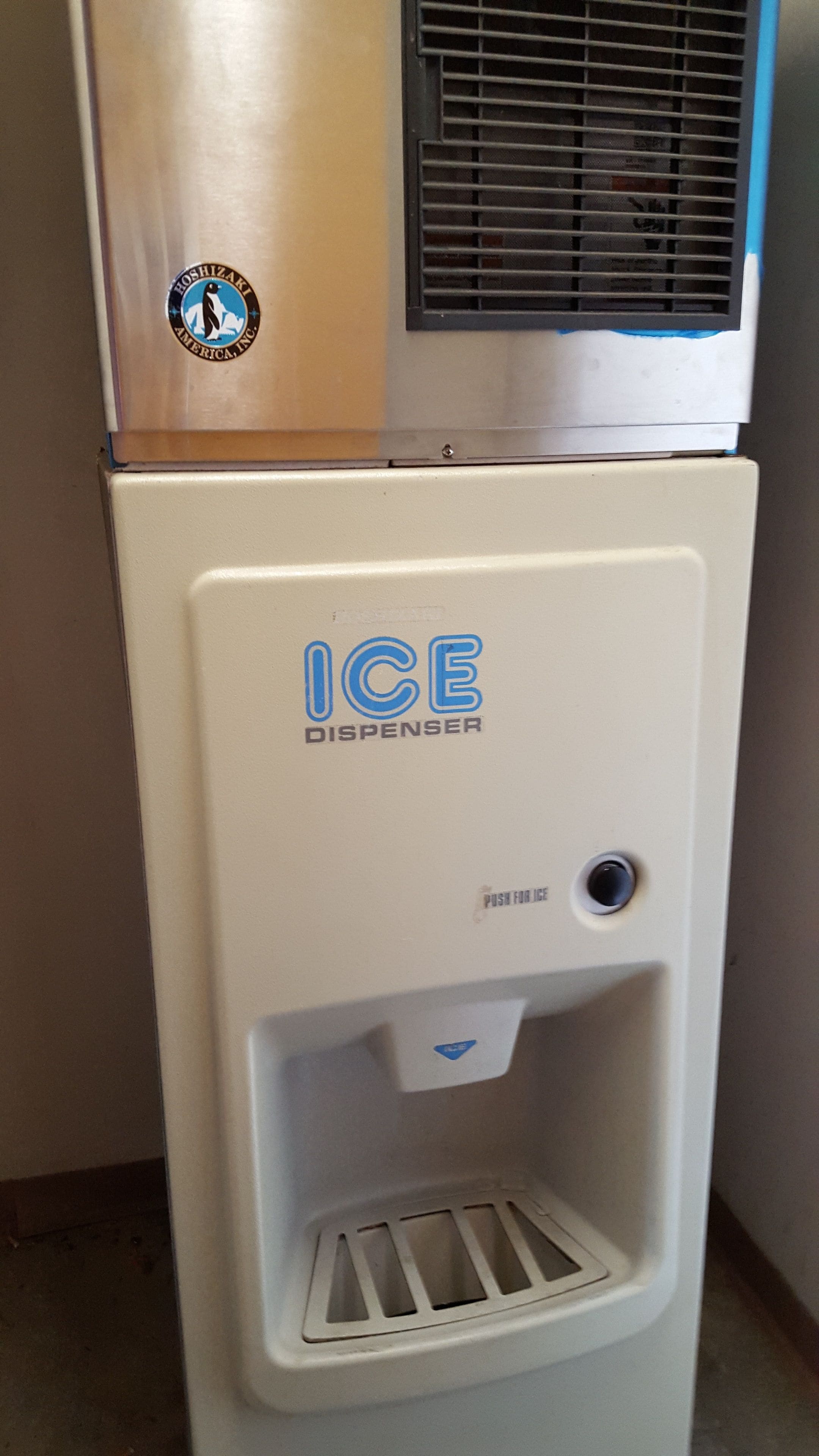 A white ice dispenser with a logo and a push button for ice.