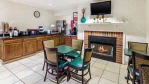Un vestíbulo de hotel con cocina, chimenea y televisor montado encima.