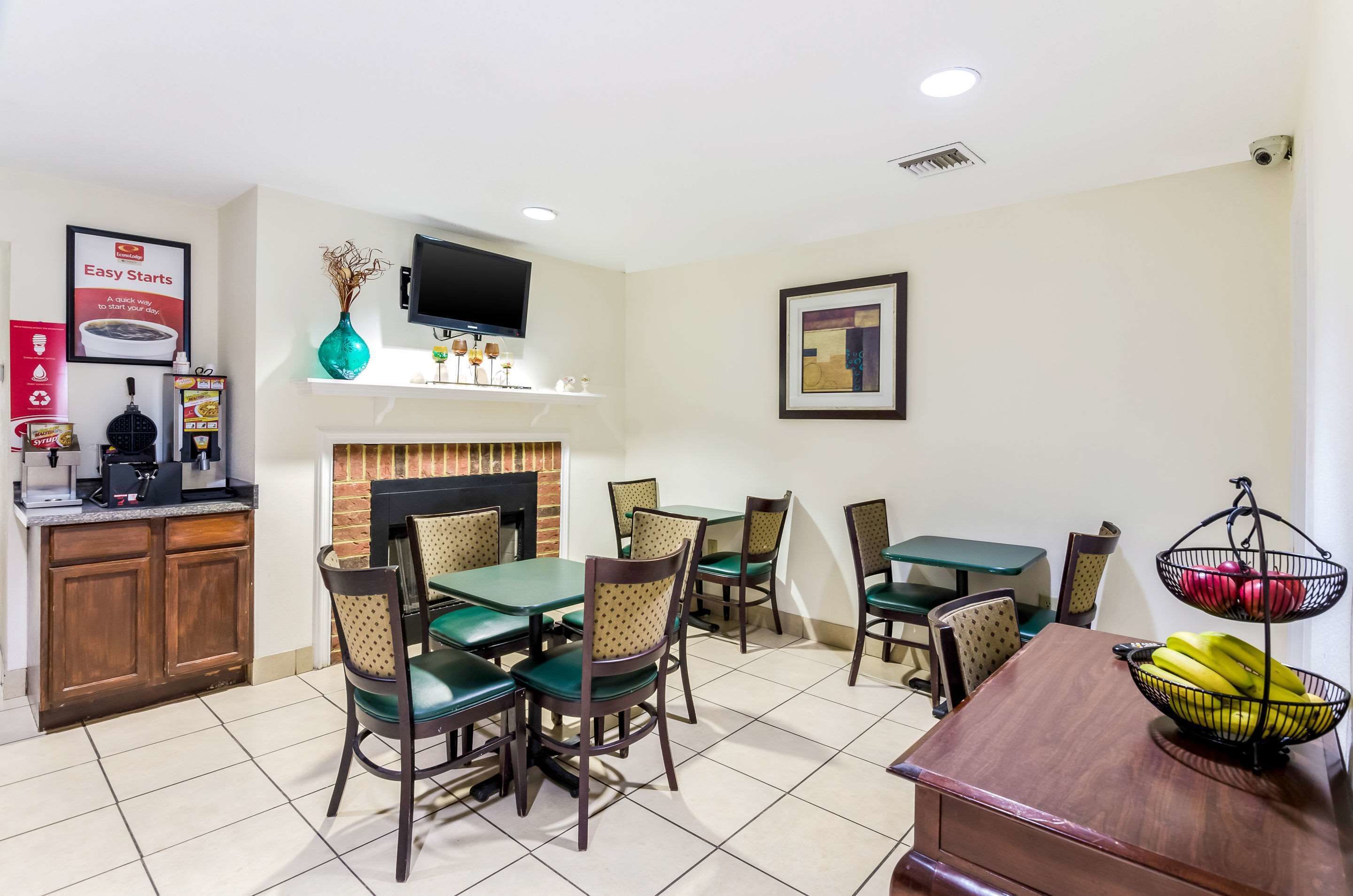 A dining area with a fireplace, a TV mounted above it, and a variety of chairs and tables.