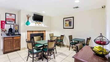 A dining area with a fireplace, a TV mounted above it, and a variety of chairs and tables.