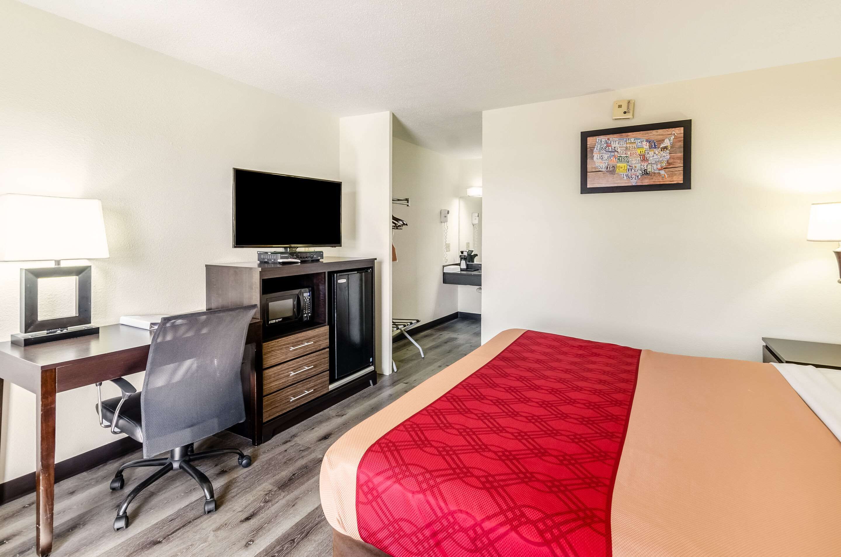 Habitación de hotel con cama, escritorio, silla, televisor y un mapa en la pared.