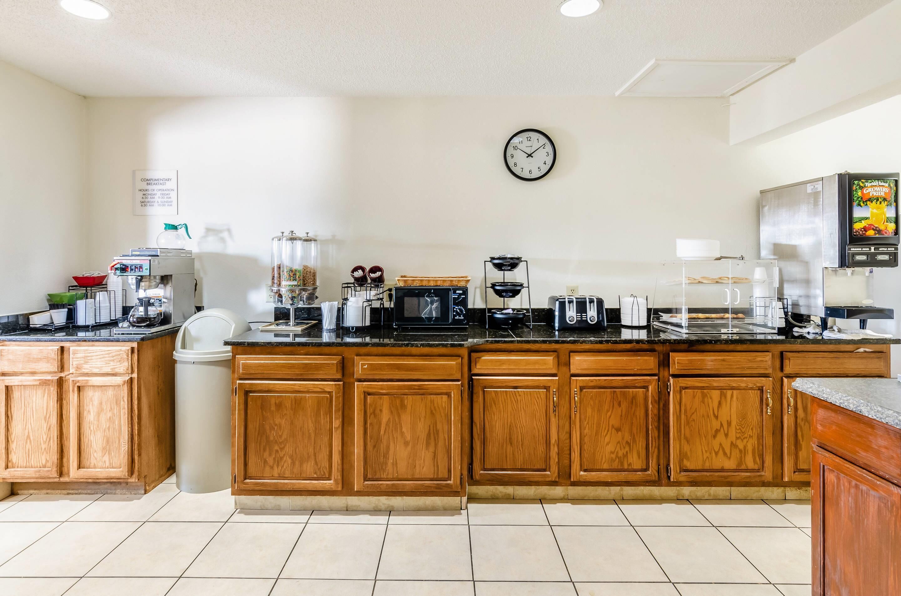 Una cocina con armarios de madera, una cafetera, un microondas, un tostador y un refrigerador.