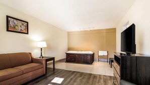 Habitación de hotel con sofá, cama, televisión, escritorio y lámpara.