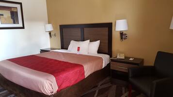 A hotel room with a large bed, two bedside tables, a desk with a phone, and a chair.