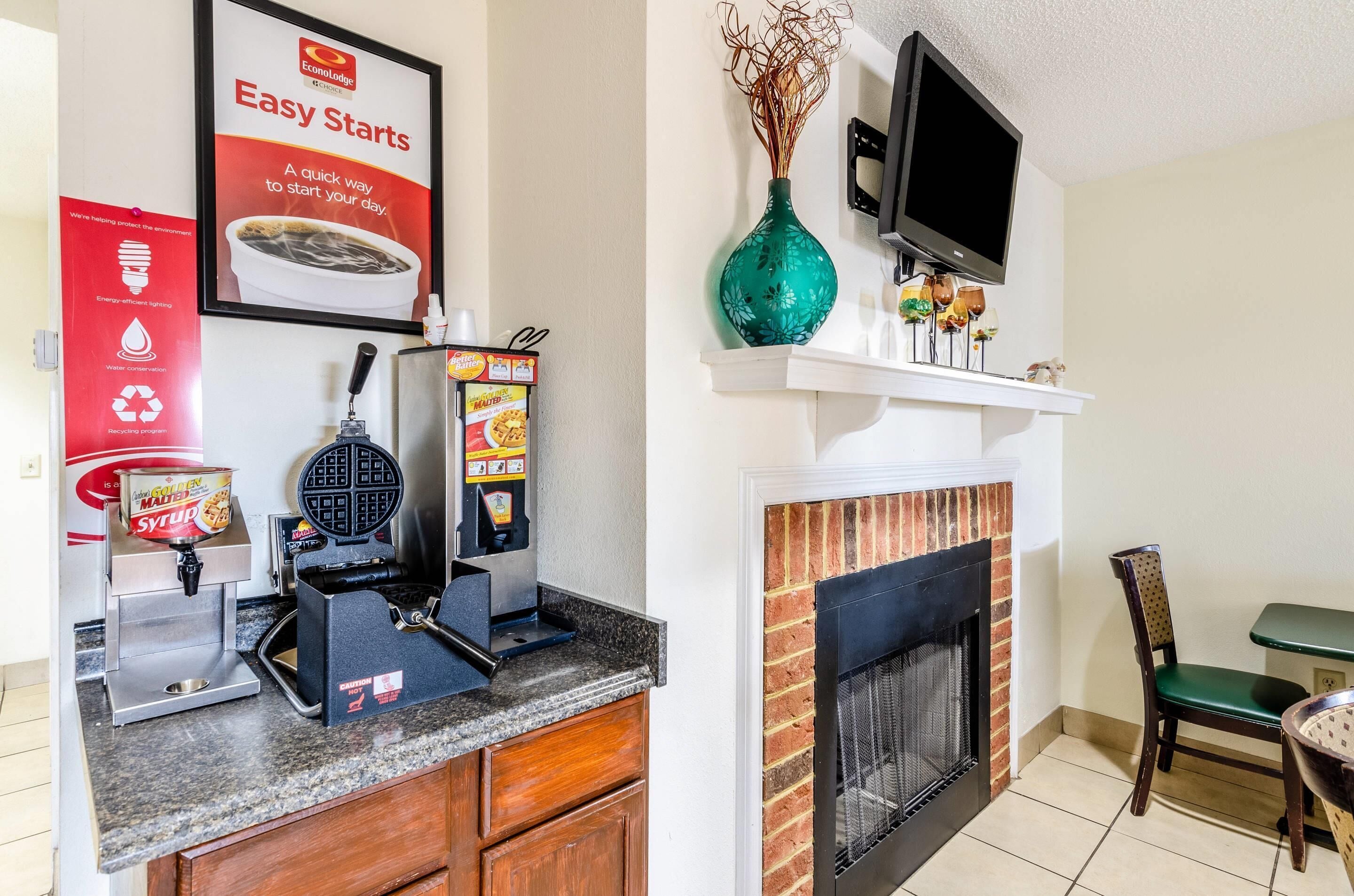 A kitchen with a waffle maker, a coffee machine, and a sign about energy-efficient lighting.