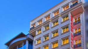 Un hôtel à plusieurs étages, doté d’une architecture classique, avec des balcons aux étages supérieurs et une enseigne d’hôtel bien visible.