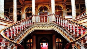 Un magnifique escalier, orné de balustrades et de colonnes travaillées, menant à une porte en arc de cercle.