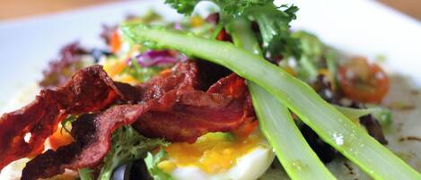 A close-up of a breakfast dish with bacon, egg, and vegetables on a plate.