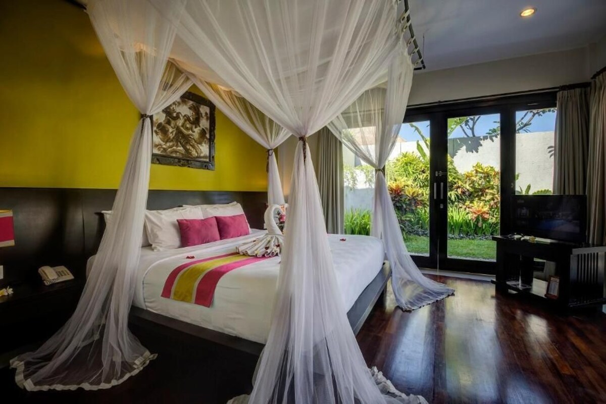 Quarto com cama de dossel, televisão e vista para o exterior.
