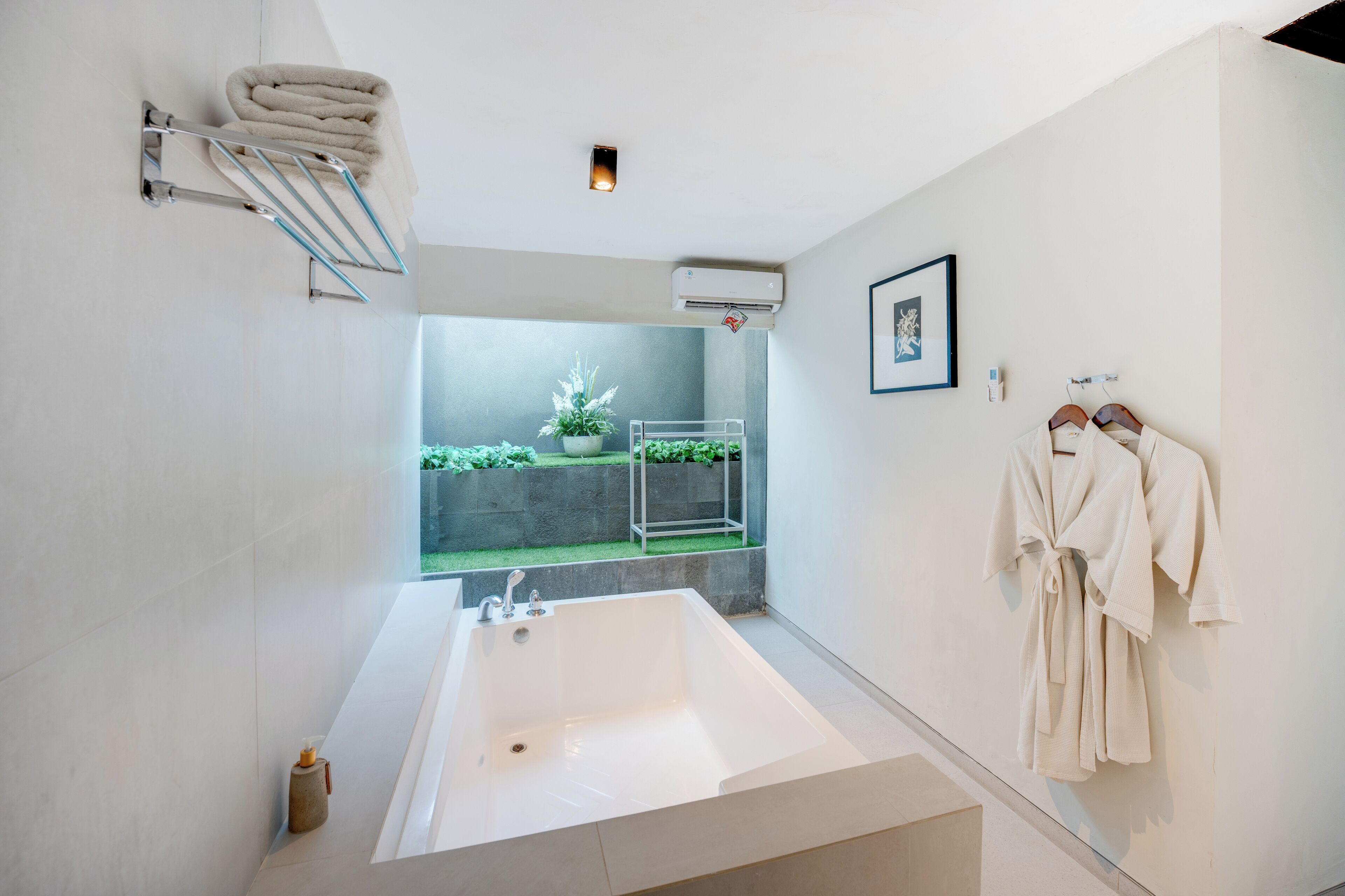 Une salle de bain moderne avec une grande baignoire, un porte-serviettes et une petite plante en pot.