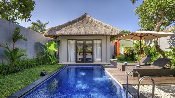 A poolside area with a thatched-roof structure, lounge chairs, and a clear blue pool. - Villa Jerami & Spa (Seminyak)